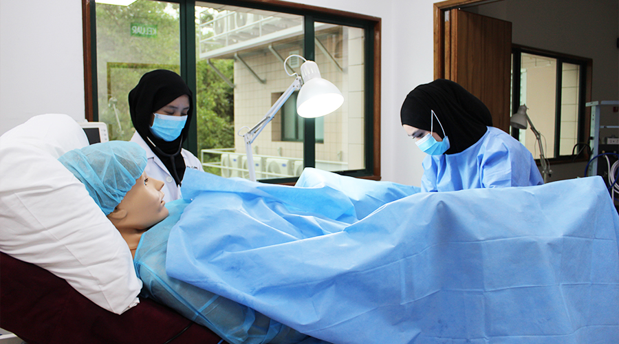 Nursing Course in Brunei | female students JCHS surgical mask desk lamp hospital bed pillow nursing manikin clinical training classroom to ward